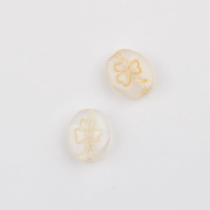 Close-up of two white oval Czech glass beads with golden clover pattern for DIY jewelry