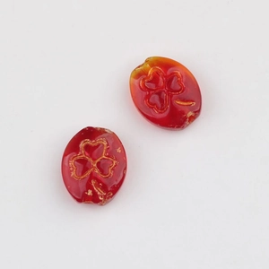 Close-up of Czech glass beads featuring red-orange gradient and gold clover embossing