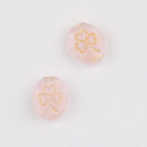 Detail of pink translucent clover beads with gold-rimmed patterns for DIY jewelry
