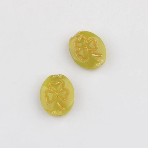 Detail of green oval glass beads featuring a golden etched shamrock pattern for DIY jewelry