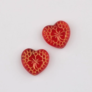 Macro detail of red heart-shaped Czech beads with vintage gold floral pattern for DIY jewelry