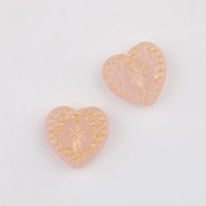 Detail of pink heart-shaped glass beads with gold clover patterns for DIY jewelry making