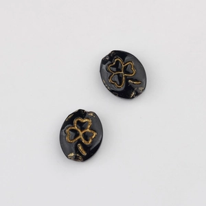 Detailed view of black oval glass beads with vintage gold clover etching for DIY jewelry