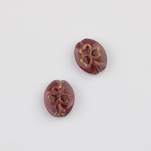 Macro view of dark purple glass clover beads with vintage gold embossing and thread hole