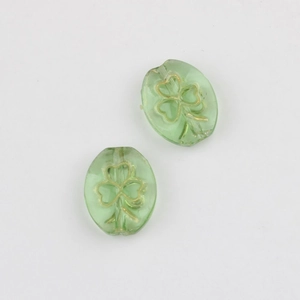 Macro view of two green clover glass beads with gold outline for DIY jewelry making