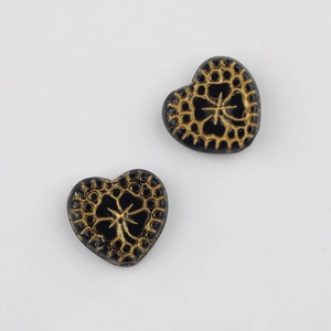 Macro detail of heart-shaped Czech glass beads with vintage gold floral pattern