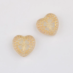 Macro shot of heart-shaped Czech glass beads with gold-trimmed honeycomb patterns