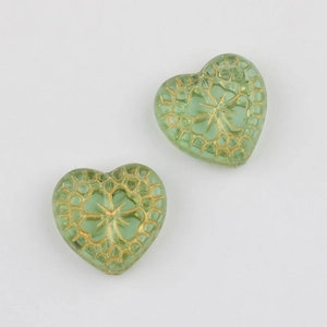 Close-up of green heart-shaped Czech beads with vintage gold floral patterns