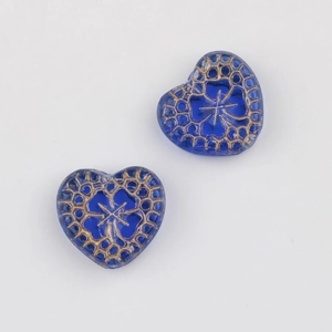 Macro detail of blue heart-shaped Czech glass beads with ornate gold vintage patterns