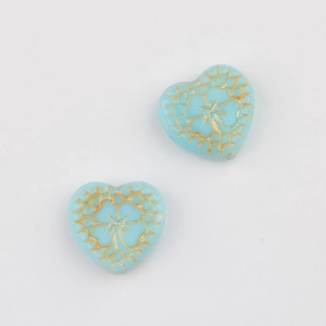 Macro detail of heart-shaped Czech beads with gold floral patterns for DIY jewelry