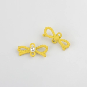 Detalle de lazos amarillos con perlas y textura granular para accesorios de joyería