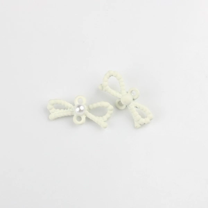 Detalle de colgantes de lazo blanco crema con textura de cuentas y perla central