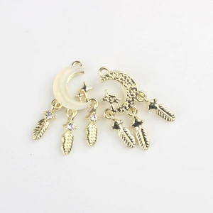 Détail de pendentifs lune et plume dorés avec incrustation de résine blanche élégante