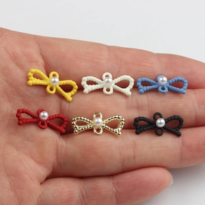 Conectores de joyería con forma de lazo multicolor y perlas mostrados en la mano