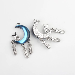 Detailed view of silver crescent moon charms with blue resin and feather tassels