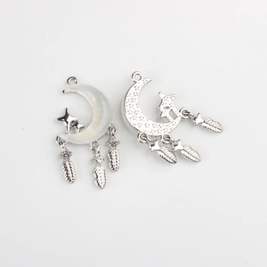 Detailed macro view of silver moon pendants with resin inlay and feather charms