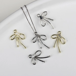 Detalle macro de colgantes de lazo con perlas y circonitas en oro y plata pulida