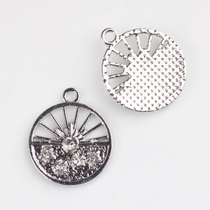 Detailed view of silver flower alloy pendants with sunburst design and pavé rhinestones