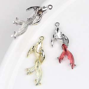 Macro detail of alloy goldfish charms with transparent resin tails for DIY jewelry