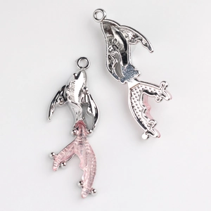 Macro detail of two dolphin charms showing silver alloy finish and pink resin tail texture