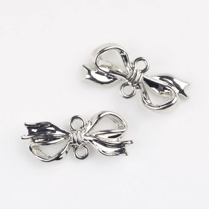 Detail view of silver metal bow pendants with double loops for DIY jewelry making