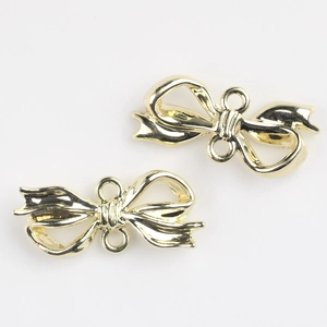 Macro detail of golden alloy bow charms with dual connecting rings for DIY jewelry