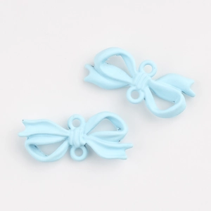 Detail view of two light blue matte bow pendants with dual loops for DIY jewelry making