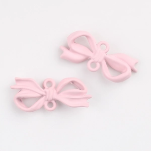 Macro detail of matte pink bow jewelry pendants with dual loops for DIY crafting