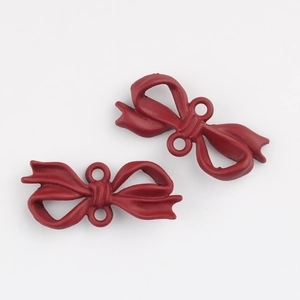 Detail showing two dark red matte bow-knot alloy pendants for DIY jewelry making