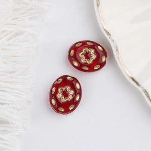 Detailed macro of dark red glass beads with gold flower pattern and polished finish