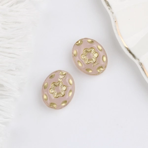 Macro detail of Czech glass beads with gold floral relief on a soft pink base