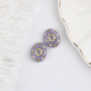 Detailed macro of vintage purple Czech glass beads with embossed gold flower patterns