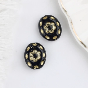 Detailed close-up of Czech glass beads with gold floral patterns and black finish