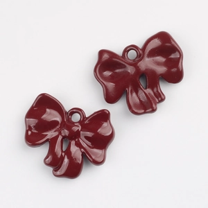 Close-up of a pair of dark red lacquer bow charms with metal rings for DIY jewelry making