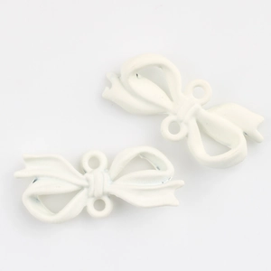 Detail view of white enamel bow charms for DIY jewelry making with dual connection rings
