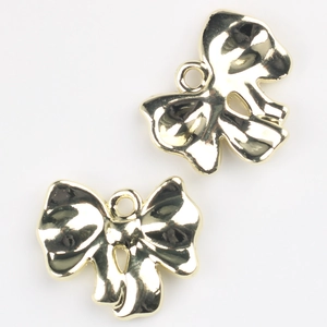 Detail of two gold-colored bow charms with hanging holes for DIY jewelry making