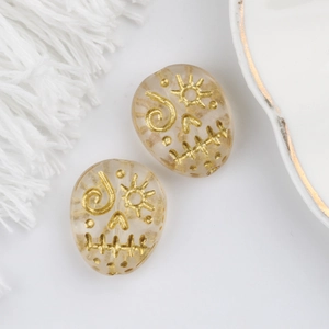 Macro view of two frosted glass oval beads with golden sun patterns for jewelry DIY