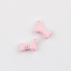Close-up of pink bone-shaped alloy pendants with paw prints for DIY jewelry making