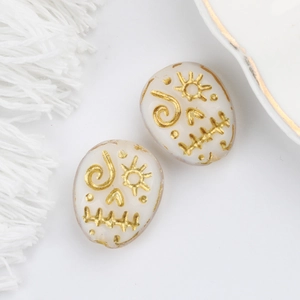 Macro shot of Czech glass skull beads with vintage gold hand-painted sun and spiral motifs