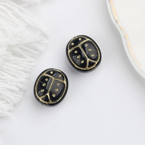 Macro shot of two black glass beetle beads with hand-painted gold beetle engravings