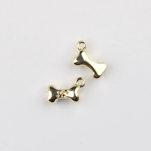 Macro shot of two golden bone charms with paw print engraving for DIY jewelry making