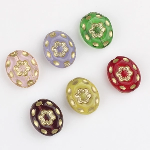 Flat lay of oval Czech glass beads with gold flower relief for DIY jewelry making