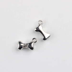 Close-up of bone-shaped metal pendants with paw print for DIY jewelry making