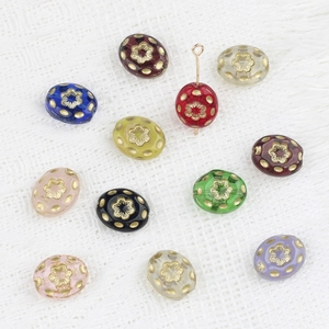 Detailed view of Czech glass beads with gold flower patterns and metallic T-pin