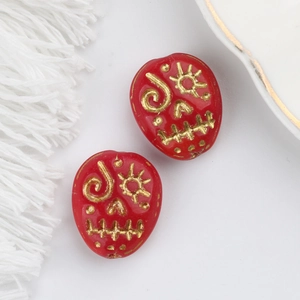 Detail of red Czech glass skull beads with gold engraved sun patterns for DIY jewelry