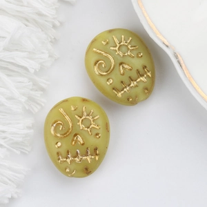 Close-up of Czech glass beads with gold painted sun face and totem patterns for jewelry DIY