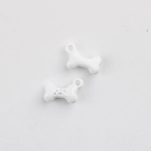 Close-up of white enamel bone charm with paw print detail and hanging loop for DIY jewelry