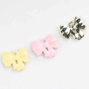Detail of colorful bow-shaped alloy pendants with polished finish for DIY jewelry crafting