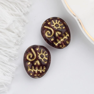 Macro detail of Czech glass beads with gold skull engraving for DIY jewelry making