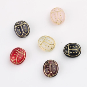 Macro detail of handmade Czech glass scarab beads with gold hand-painted accents for DIY jewelry